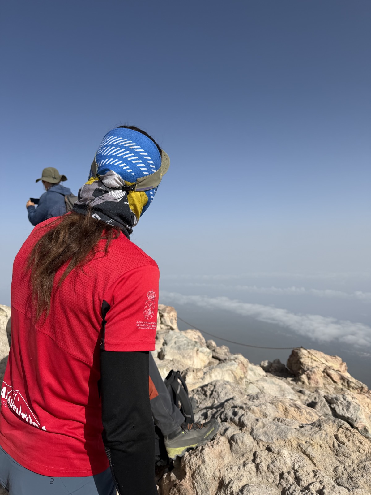 Hiker standing above a solid sea of clouds stretching to the horizon from high on Mount Teide