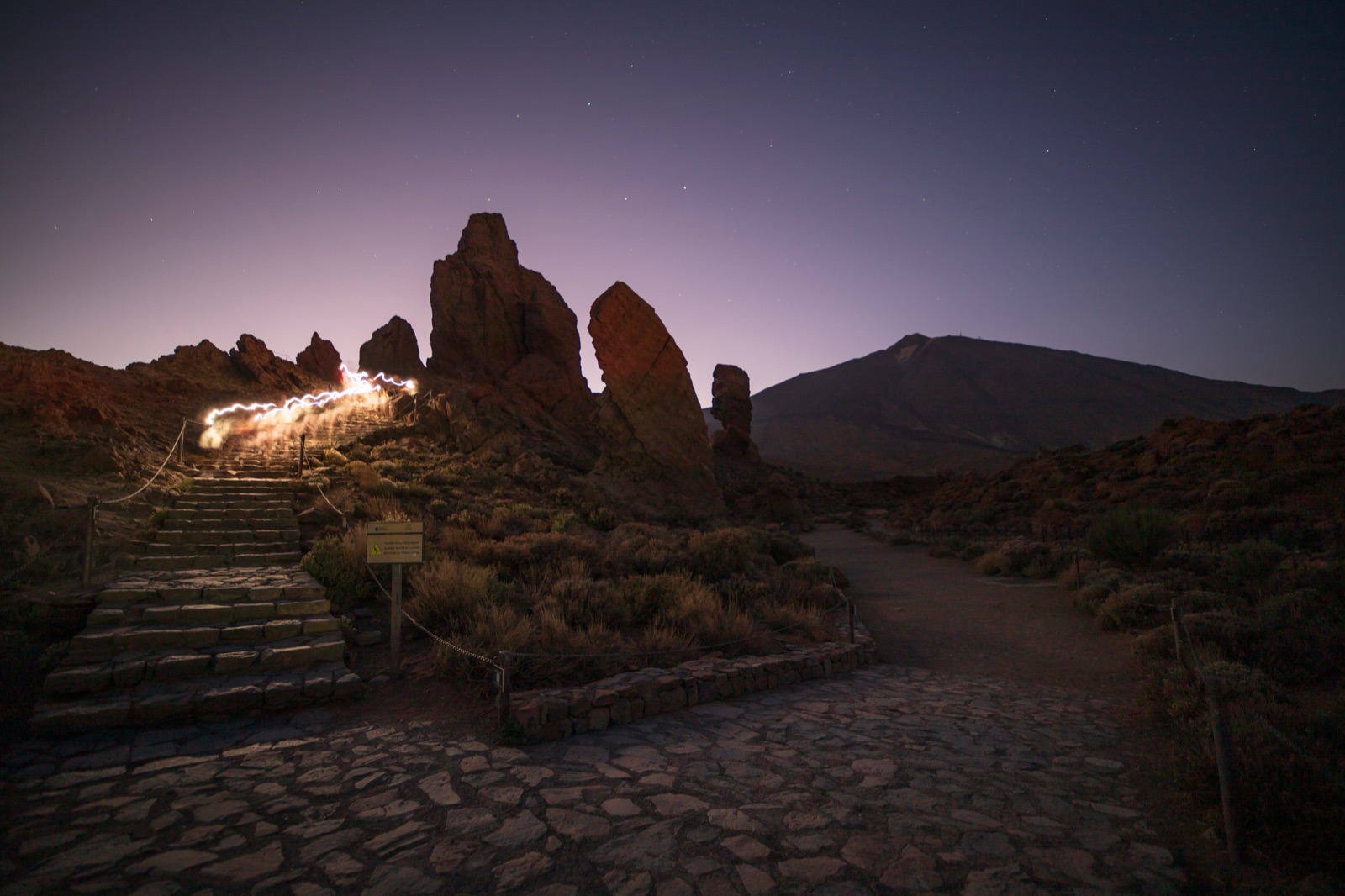 Stone steps at Roques de García at dusk with stars and headlamp light trails